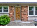 Close-up of a rustic wooden front door flanked by windows, set in a brick facade at 7180 W Sacramento Dr, Greenfield, IN 46140