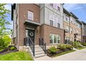 Close up of a charming townhouse with a brick facade, a wreath on the door, and landscaped front yard at 8180 E 116Th St, Fishers, IN 46038
