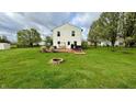 Expansive backyard featuring a large grassy area, a wooden deck, a stone fire pit, and mature trees at 18017 Gasparilla Ct, Westfield, IN 46062
