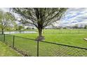 A serene backyard view with a pond, a spacious grassy area, a fence, and mature trees at 18017 Gasparilla Ct, Westfield, IN 46062