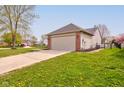 View of the backyard showing a driveway, grassy yard, vinyl siding, and two car garage at 2075 Sea Hero Ct, Indianapolis, IN 46234