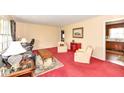 Comfortable living room with classic furnishings, leading to the kitchen area, with plush red carpeting at 5927 Pine Hill Dr, Indianapolis, IN 46235