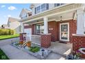 Inviting front porch with brick pillars, white railing, and decorative flower pots at 621 Sonoma Ln, Greenfield, IN 46140