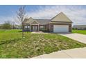 Well maintained brick home with attached garage and manicured lawn with lovely walkway leading to the front door at 6606 Colt Ln, Anderson, IN 46013