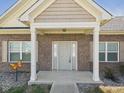 Inviting front entrance with a covered porch and a beautiful brick facade with manicured greenery and stone walkway at 6606 Colt Ln, Anderson, IN 46013