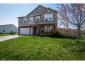 Charming two-story home with green lawn, mature tree, and front porch decorated with an American flag at 717 Driftwood Cir, Danville, IN 46122