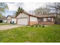 This charming home features a two-car garage, neutral siding, brick accents, and a well-manicured front lawn at 9143 Warwick Rd, Indianapolis, IN 46240