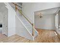 Bright foyer with a staircase featuring white trim and wood railing, complemented by hardwood floors at 9318 Windrift Way, Zionsville, IN 46077
