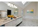 Bright bathroom with marble floors, dual sinks, skylight, and a soaking tub at 950 Nevelle Ln, Carmel, IN 46032