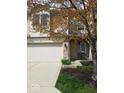 Inviting townhome with a two-car garage, brick details, and a cozy entrance framed by blooming landscaping at 11264 Fonthill Dr, Indianapolis, IN 46236