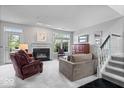 Bright living room with a cozy fireplace, staircase, large windows and neutral decor at 11264 Fonthill Dr, Indianapolis, IN 46236