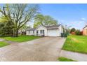 Inviting single-story home with a long driveway, lush green lawn, and attached one-car garage at 1213 Fairview Dr, Greenfield, IN 46140