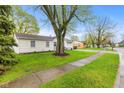 Well-kept ranch home with green lawn, landscaping, and a mature tree providing ample shade at 1213 Fairview Dr, Greenfield, IN 46140