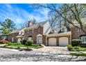 Charming brick townhome featuring attached garages, manicured landscaping, and classic architectural details at 13587 Kensington Pl, Carmel, IN 46032