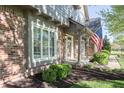 Inviting brick front porch with American flag, green shrubs, and decorative windows at 13948 Silver Stream Dr, Carmel, IN 46032