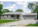 Attractive single-story home with gray brick, a two-car garage, a gravel driveway, and front yard at 6223 N Parker Ave, Indianapolis, IN 46220