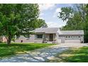 Lovely brick home with attached garage surrounded by mature trees and a gravel driveway at 6223 N Parker Ave, Indianapolis, IN 46220