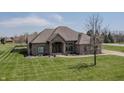 Beautiful single-story brick home with lush green lawn, a mature tree, and a welcoming covered entryway at 6472 Independence Ct, Pendleton, IN 46064