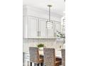 Bright kitchen features white cabinets, chic backsplash, stylish pendant lights, and breakfast bar with woven chairs at 8327 Andrusia Ln, Indianapolis, IN 46237