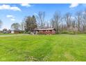 A well-maintained lawn surrounds a charming single-story home with a detached two-car garage and mature trees at 874 S Sycamore Dr, Greenfield, IN 46140