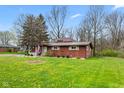 Lovely single-story home with a cozy front porch adorned with the American flag and lush, green landscaping at 874 S Sycamore Dr, Greenfield, IN 46140