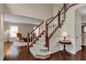 Elegant foyer features hardwood floors, a staircase with white rails, and a view into the living area at 9319 Oak Knoll Ln, Fishers, IN 46037
