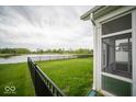 Beautiful backyard with a screened-in porch, green lawn, and a serene view of the lake at 9455 Orchard Cove Dr, Indianapolis, IN 46239