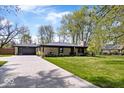 Lovely single story home with a long driveway, well-manicured lawn, and mature shade trees at 9944 Holaday Dr, Carmel, IN 46032