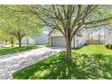 View of the property from the driveway with plenty of green grass and lush trees at 11651 Beardsley Way, Fishers, IN 46038