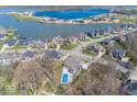Aerial view showcasing the lake community, featuring a home with a pool surrounded by lush greenery and other houses at 13705 Beam Ridge Dr, McCordsville, IN 46055