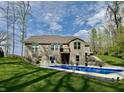 An expansive backyard features a pristine pool, lush landscaping, and a well-maintained lawn under a partly cloudy sky at 13705 Beam Ridge Dr, McCordsville, IN 46055