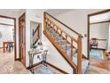 Inviting entryway with a wooden staircase, decorative mirror, tile flooring, and warm lighting fixtures at 2011 Pin Oak Ct, Indianapolis, IN 46260