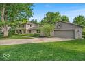 A well-maintained home showcasing stone accents, an attached garage with a basketball hoop, and manicured landscaping at 2011 Pin Oak Ct, Indianapolis, IN 46260
