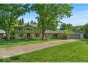Charming two-story home with lush landscaping, stone accents, and a long driveway leading to an attached garage at 2011 Pin Oak Ct, Indianapolis, IN 46260