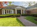 Beautiful brick home featuring a landscaped yard, brick pathway, and a decorative wrought iron door at 411 Sugar Tree Ln, Indianapolis, IN 46260