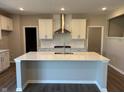 Modern kitchen featuring white cabinets, a stainless-steel range hood, and a large island with a sink at 7215 Barrett Dr, Brownsburg, IN 46112