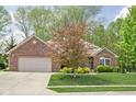 Beautiful brick home featuring a two-car garage, lush lawn, and mature landscaping at 7340 Stones River Dr, Indianapolis, IN 46259