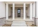 Inviting front porch with substantial brick pillars and a modern solid wood front door at 8092 Abington Way, Zionsville, IN 46077