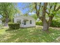 Exterior shot of a quaint single-story home featuring lush greenery, mature trees, and a well-manicured lawn at 819 E Mills Ave, Indianapolis, IN 46227