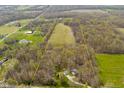 Aerial view of land parcel featuring a house, outbuildings, wooded area, and expansive open field at 9570 S 300 W, Columbus, IN 47201
