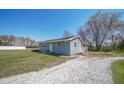 Exterior shot of home showcasing blue siding, well-maintained grounds, and gravel driveway at 1004 Shepherd Rd, Anderson, IN 46012