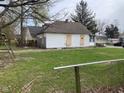View of a fenced backyard with grass and a building with boarded up windows at 1924 E Maryland St, Indianapolis, IN 46201