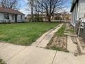 View of a spacious backyard with a long driveway, green grass, and some dandelions growing around at 1924 E Maryland St, Indianapolis, IN 46201