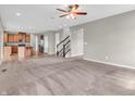 Open-concept living room with stairs and entry to kitchen, neutral walls, carpet, and a ceiling fan at 1968 Saratoga Dr, Greenwood, IN 46143