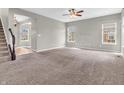 Spacious living room featuring neutral walls, plush carpet, ceiling fan, and ample natural light from multiple windows at 1968 Saratoga Dr, Greenwood, IN 46143