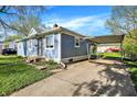 View of light blue single-story home with a carport, lush green grass, and a tidy exterior at 3538 Cecil Ave, Indianapolis, IN 46226