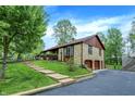 Unique stone house with an attached garage, brown roof, and a lush green lawn with wooden walkway at 3875 Arrowhead Ct, Greenfield, IN 46140