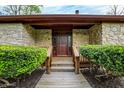 A charming stone home with a wooden walkway leading to the front door, framed by manicured shrubbery at 3875 Arrowhead Ct, Greenfield, IN 46140