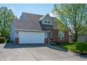 Charming home with a lush green lawn, a mature tree, brick accents, and an attached two car garage at 419 Old Glory Dr, Greenfield, IN 46140