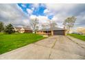 Single-story brick home includes a two-car garage with a cracked concrete driveway at 5576 N Heritage Ln, Alexandria, IN 46001